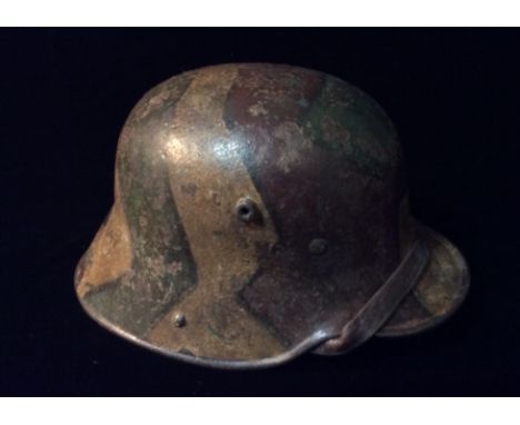 A WORLD WAR I GERMAN ARMY STEEL CAMOUFLAGE HELMET Painted with brown, red and green geometric style panels, having a pale gre