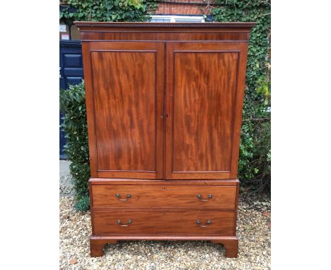 A 19TH CENTURY MAHOGANY LINEN PRESS Having a dentil frieze above panelled doors enclosing a hanging rail over two long drawer