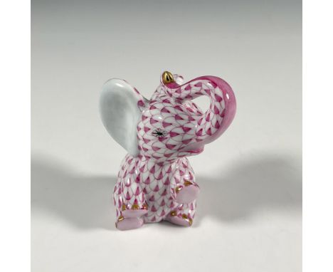 Hand painted figure of a seated young elephant with its trunk curled up to its head. Decorated in a pink scale pattern. Heren