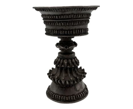 19th century Tibetan silver butter lamp, the bowl with everted rim, the stem with embossed lotus petals on a swept conical fo