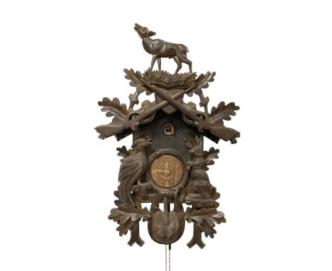 Two German weight driven cuckoo clocks. A large mid 20th century carved case cuckoo clock with a two train movement, cuckoo s