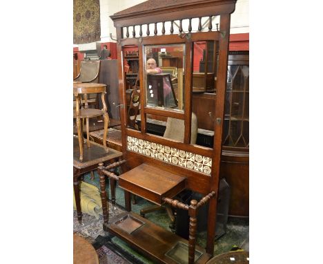 A late Victorian oak hallstand, architectural pediment, spindled back over rectangular plate, tile back above glove box, turn