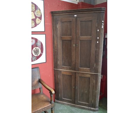 A George III floor standing oak corner cupboard of large proportions, stepped cornice, two panel door cupboard to top, simila