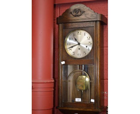 An oak cased Art Deco style wall clock, Arabic numerals, pendulum and key