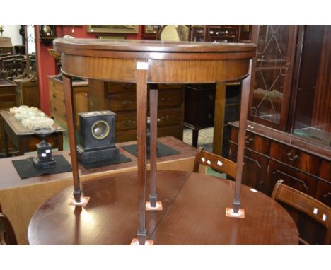 An Edwardian mahogany demi-lune card table, the top opening to green baize playing surface, tapering square legs, spade feet.