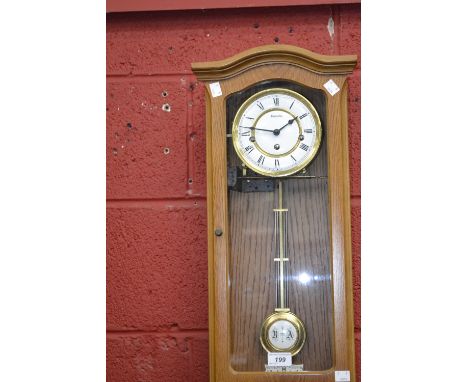 A Hermle light oak cased wall clock, Roman numerals, pendulum and key