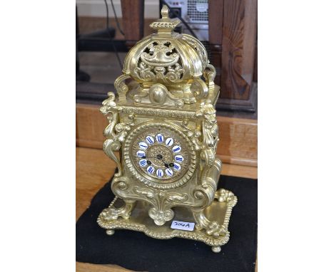 A brass mantel clock cast with dragon heads and claws, Roman numerals.