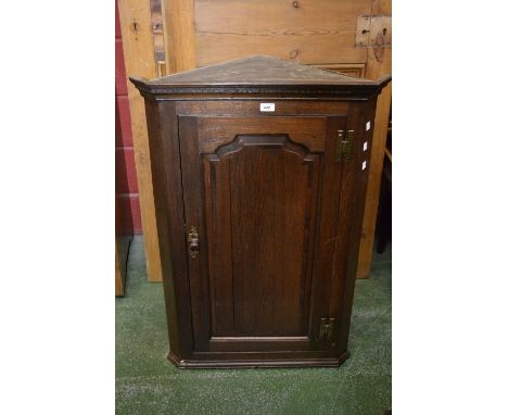 A George III oak splay front wall mounted corner cupboard, outswept cornice, dentil frieze, fielded shaped panel door, circa 