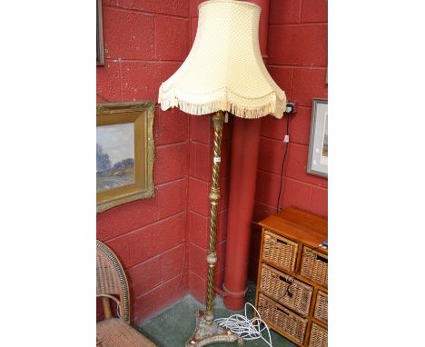 A brass standard lamp, twisted column, acanthus leaf finial, standing on three lion's paw feet with pale lemon shade (PAT tes