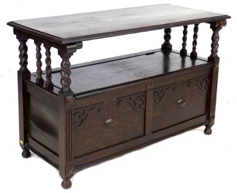 A stained and carved oak monk's bench, mid 20th century, with lifting and sliding top, and lift seat revealing a storage comp