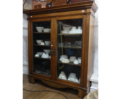 A Victorian oak glazed Bookcase, the moulded dentile cornice above the two glazed doors, enclosing a shelved interior, flanke