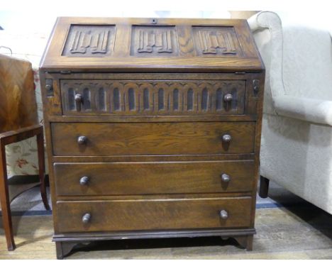 An antique-style oak Bureau, the hinged lid with scroll incised decoration, with fitted interior, upon four long drawers of v