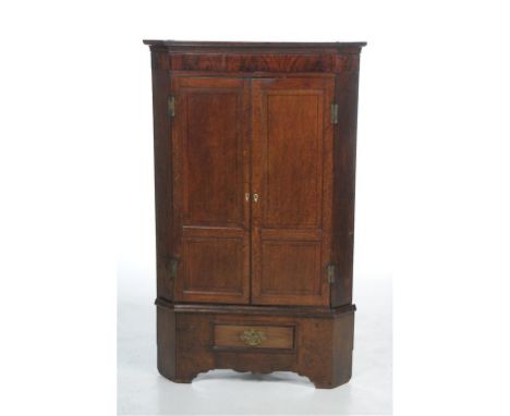 Early 19th century oak and mahogany crossbanded hanging corner cupboard on stand, with a cavetto cornice above a mahogany fri