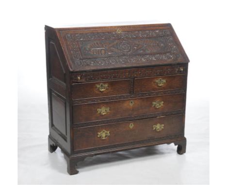 An 18th century oak and later carved bureau, the hinged fall front carved with a lozenge, leaves and frieze of flowers with a