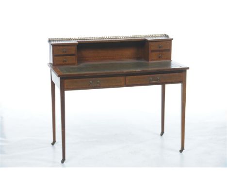 An Edwardian inlaid mahogany and satinwood crossbanded writing desk with a gilt metal gallery above four frieze drawers, inse