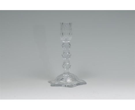 An early 19th century glass table candlestick with a petal shape base rising to a facet cut baluster stem, 21.5cms