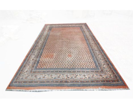 A North West Persian carpet, the red ground with guard stripes with a frieze of stylised flowers and leaves, the central grou