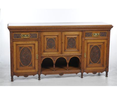 A late 19th century carved oak sideboard, the rectangular top above a dentil frieze and a pair of cupboard doors, each centre