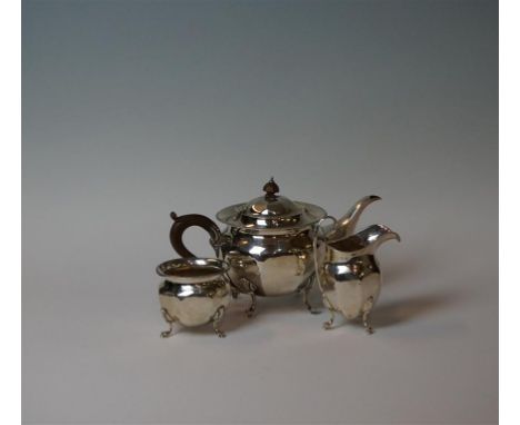 A George V hallmarked silver three piece tea service, having panelled decoration below a cast rim, made by Ernest Diruiff & C