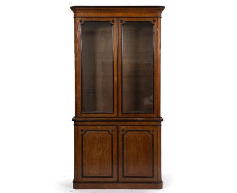 A 19TH CENTURY OAK LIBRARY CABINET with ebonised mouldings, the upper glazed section enclosing adjustable shelves, the lower 