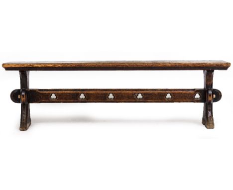A VICTORIAN OAK BENCH with shaped end supports and pierced trefoil decoration to the stretcher, 152cm wide x 29cm deep x 45cm