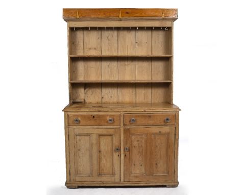 AN OLD PINE DRESSER with two shelf plate rack above and cup hooks, the base with two drawers over panelled doors with pressed