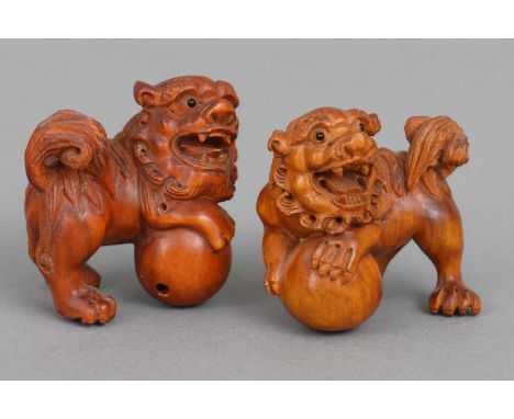Paar japanische Netsuke "Komainu" Buchsbaum geschnitzt, Löwen-Hunde mit je einer Kugel, signiert, H ca. 4cm