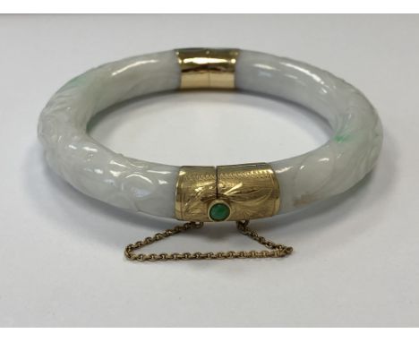 A jade bangle with high carat gold mounts