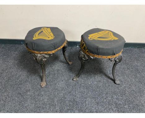 A pair of vintage cast iron bar stools on painted legs upholstered in Guinness fabric 