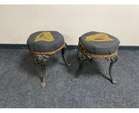A pair of vintage cast iron bar stools on painted legs upholstered in Guinness fabric 