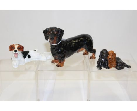 Two Royal Doulton dogs - HN1101 and HN1128 and a Royal Worcester group of three puppies