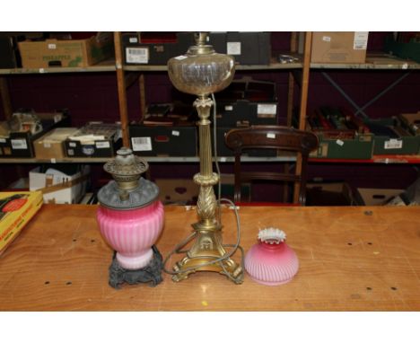 Empire-style brass table lamp with glass reservoir raised on triform base, 64cm high, together with a pink glass oil lamp (2)