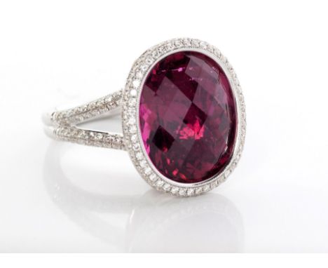 A RHODOLITE AND DIAMOND RING the tube-set oval checkerboard-cut rhodolite surrounded by two rows of 48 pavé-set round brillia