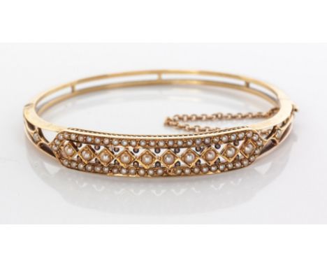 A VICTORIAN SEED PEARL BANGLE hinged, centred by 10 diamond shapes each centred by a claw-set seed pearl, surrounded by 50 pa