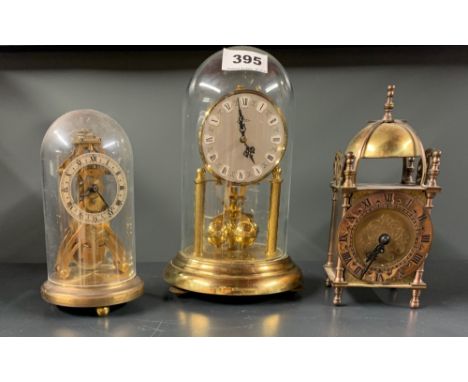 A brass lantern clock and two torsion pendulum clocks, tallest 22cm.