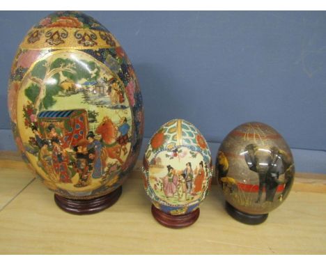 3 ceramic painted eggs, 2 with Oriental design and one with a safari scene largest 35cm. all with stands