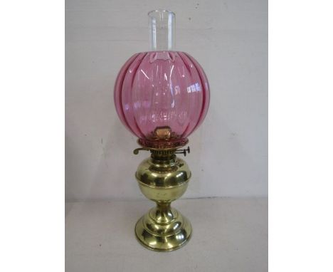 A brass base oil lamp with cranberry glass globe with spare funnel and wicks, in working order and great condition