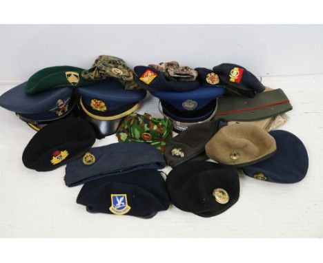 Collection of 20 military caps and berets with associated badges to include Serbia Air Force, Vietnam Army, Canadian Royal En