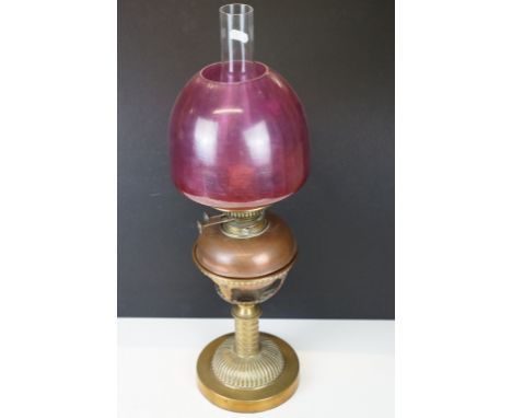 Late 19th / early 20th century brass &amp; copper oil lamp with ruby glass shade and copper font, raised on a gadrooned brass