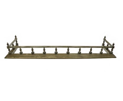 A large brass Fender, late 19th Century, with square tubular reeded top rail with urn finials on a balustrade with moulded ba