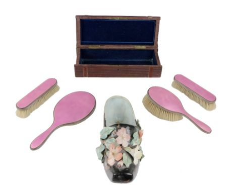 A set of 3 pink enamel and silver bracket Brushes, a matching hand mirror, a carved wooden glove box and a porcelain shoe. (6