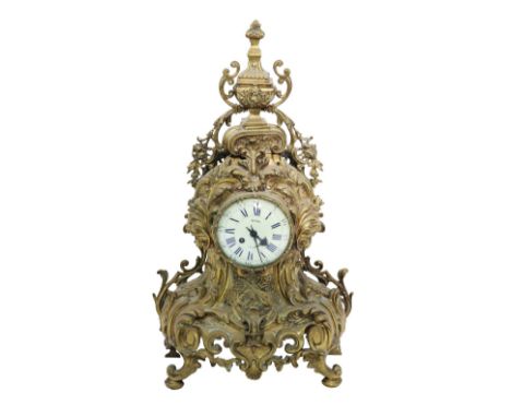 A Louis XV style French brass rococo design Mantle Clock, with urn finial above a decorated body with enamel dial, marked Ric