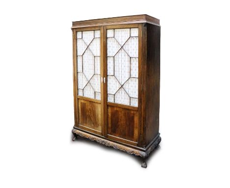 A mahogany Wardrobe, in the Chippendale style, with moulded cornice above two astragal glazed doors on a leaf carved base and