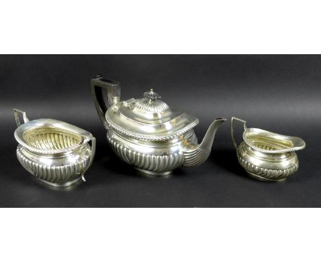 An Edwardian three piece silver tea set, comprising tea pot, milk jug and sucrier, boat shaped bodies with lobed lower bowls,