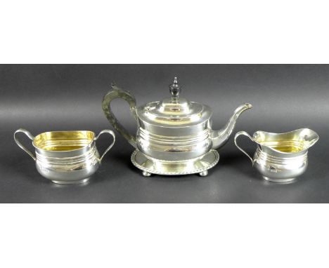 A George V silver tea set, comprising teapot, milk jug and sucrier, all with matching lobed horizontal bands to boat shaped b