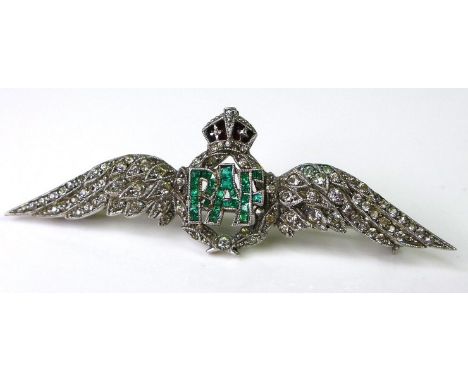 An 18ct white gold RAF dress brooch set with diamonds and emeralds, two diamond encrusted wings flanking laurel wreath with r