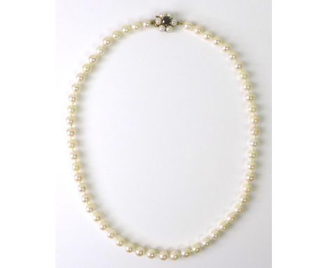 A Japanese Mikimoto cultured pearl necklace, the 9ct gold clasp set with central garnet and further pearls, with original box