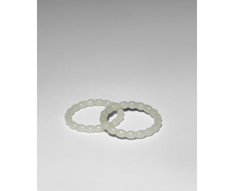 A PAIR OF CHINESE PALE CELADON JADE BANGLES QING DYNASTY OR LATER Carved as oval beads, 7.5cm. (2) PLEASE NOTE THIS LOT IS TO