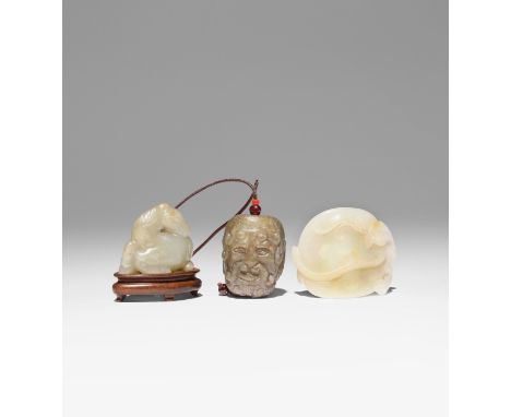 TWO CHINESE JADE CARVINGS AND A JADE HEAD PENDANT 18TH CENTURY AND LATER One in celadon jade carved as a recumbent horse with