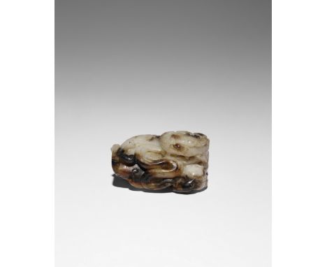 A CHINESE BLACK AND WHITE JADE CARVING OF A LION DOG QING DYNASTY The beast depicted lying down with its head turned to the r